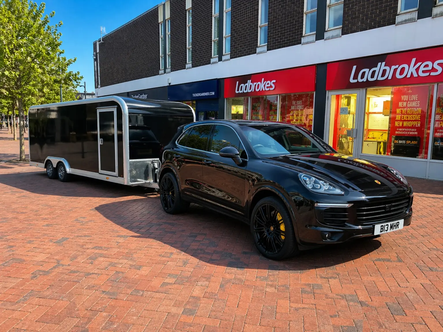 Black Porsche Cayenne beside an enclosed vehicle trailer