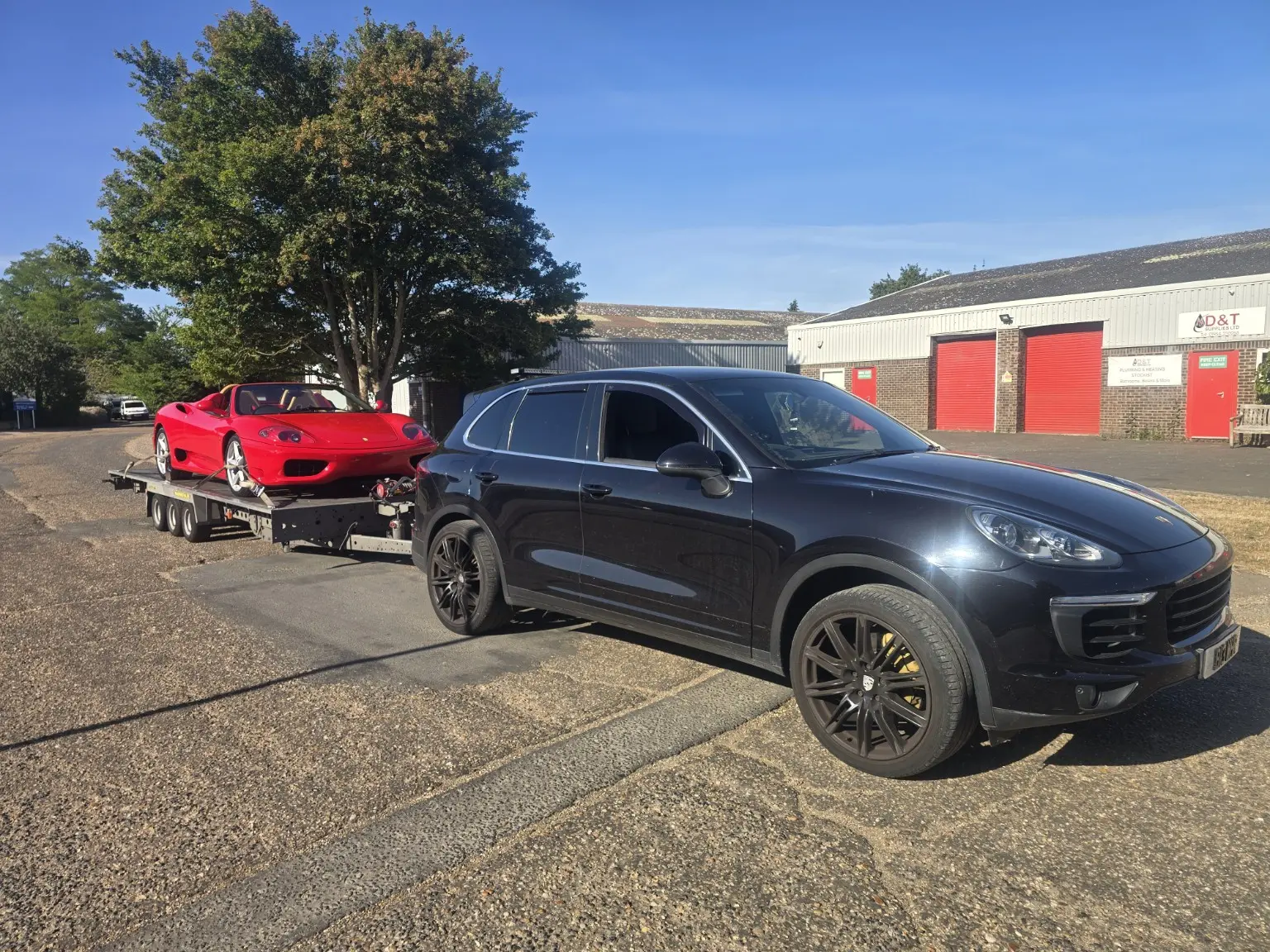 Luxury SUV towing a red sports car on a trailer